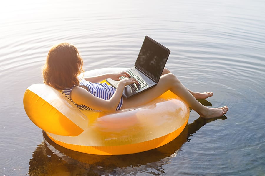 woman floating in an innertube with a laptop