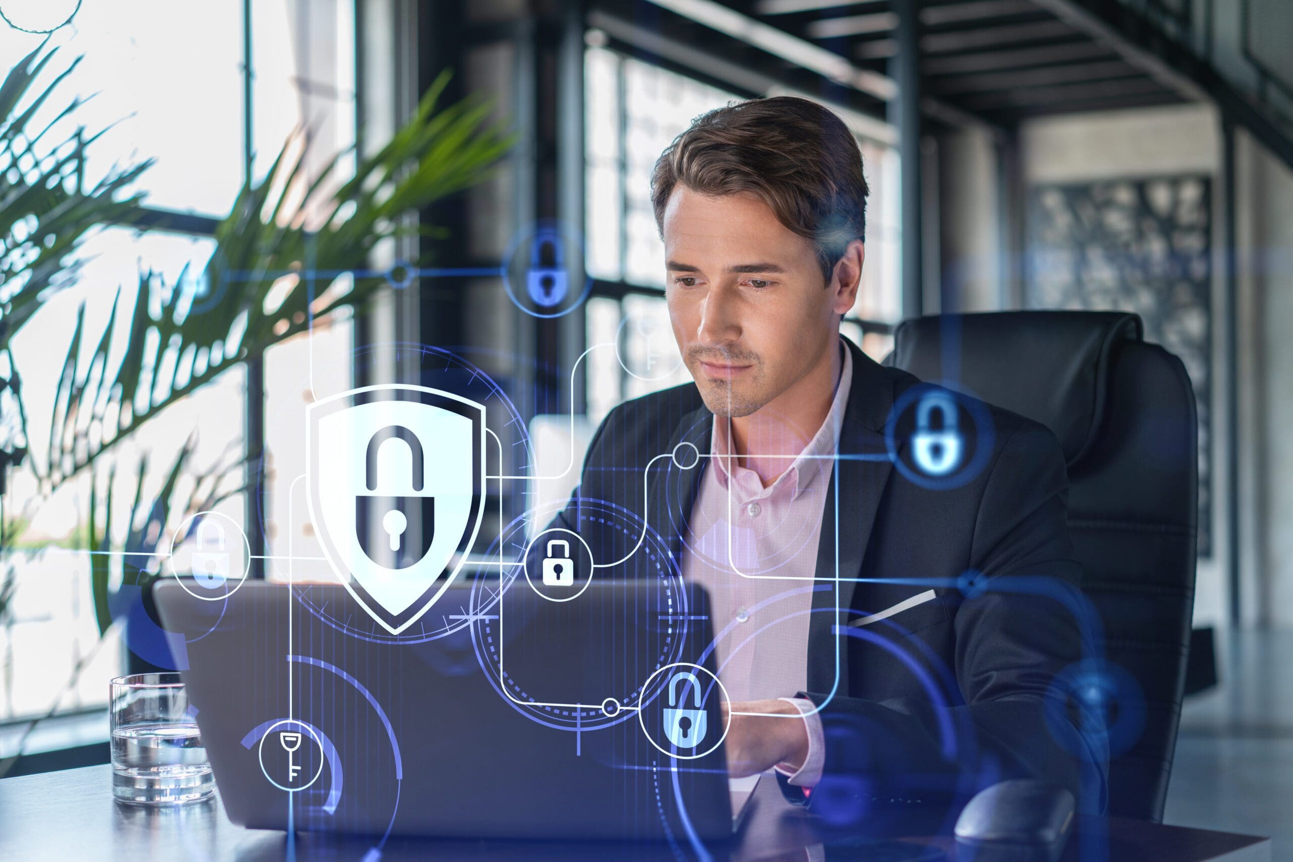 A man in a business suit works on his laptop with network security icons displayed on top.