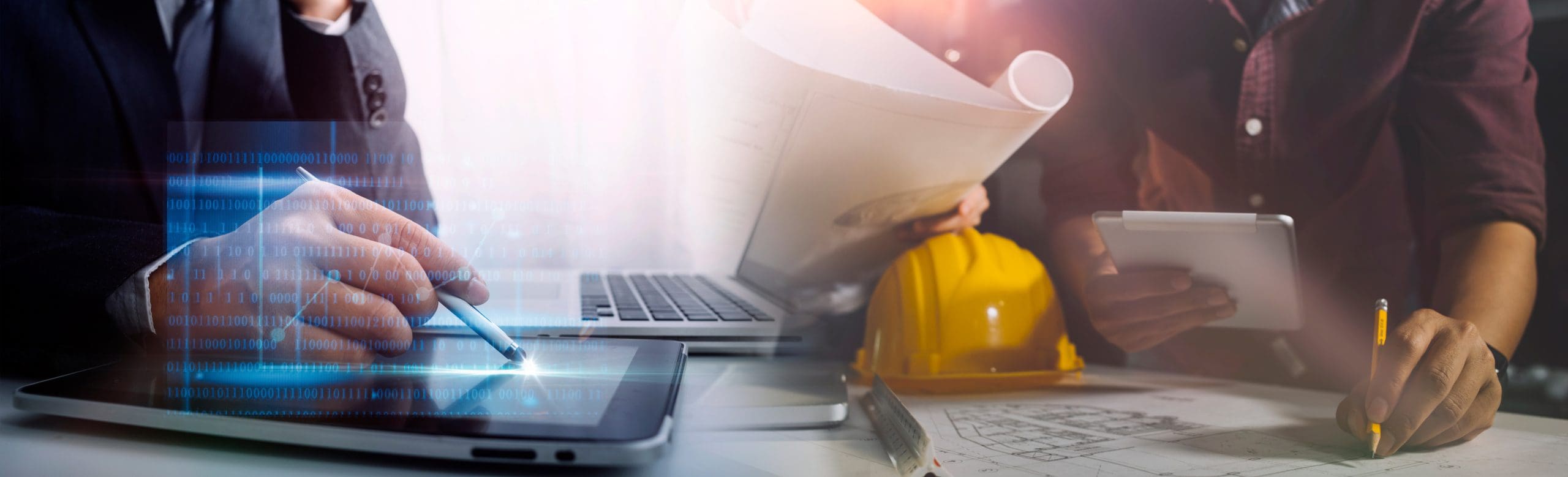 Two colleagues working on construction project at a desk with tablet and laptop