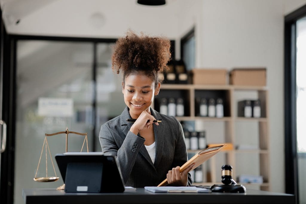 A lawyer smiles and looks down at her tablet.