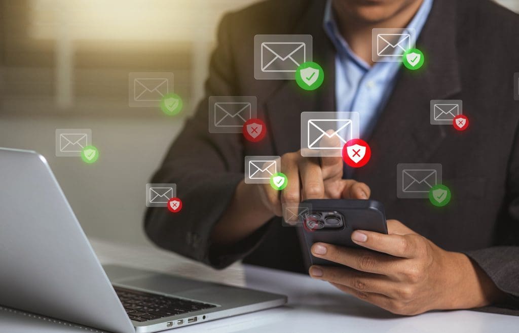 A man using his laptop and cell phone to view emails.