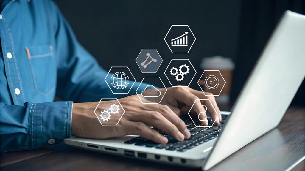 A person using a laptop with icons floating over the laptop.